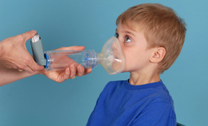 Hand pressing down on puffer with mask over child's mouth and nose