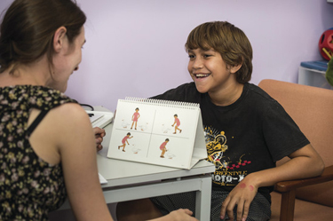 Woman sitting with young boy doing speech therapy